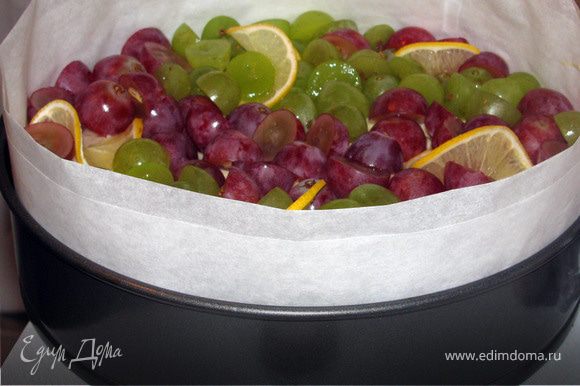Виноград вымыть, разрезать на половинки и вытащить косточки. Выложить на бисквит виноград и тонкие ломтики лимона. Поставить в холодильник охлаждаться.