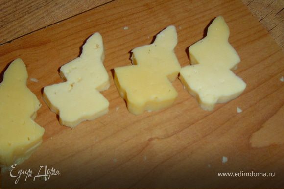 Из сыра вырезаем при помощи формочки (если нет формочки, то можно сделать шаблон, и с его помощью вырезать елочки) елочки.