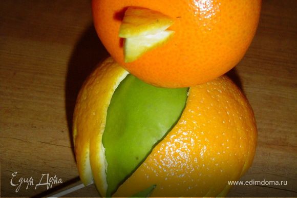 Из кожуры апельсина вырезаем два небольших треугольника, ниже центра мандарина делаем небольшое отверстие и в него вставляем эти треугольники, тем самым получая клюв.
