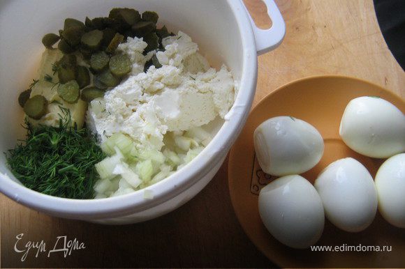Сваренные в крутую яйца охладить,очистить от скорлупы.В подходящую посуду выложить все ингредиенты:сливочное масло,творожный сыр,мелко нарезанный лук,нарезанные корнишоны,