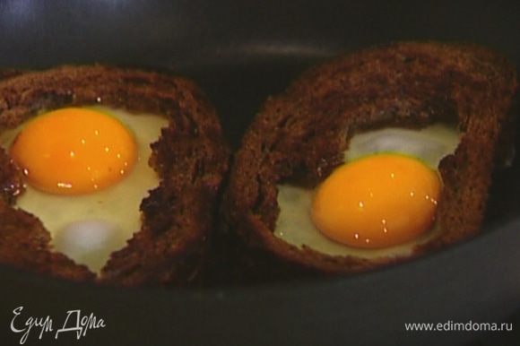 Разбить в пустую середину каждой гренки яйцо, посолить, поперчить и жарить до готовности яиц.