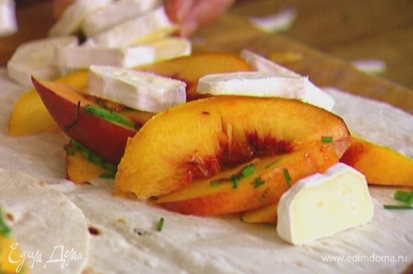 На одну половину каждого лаваша выложить персики с луком и кусочки сыра, а другой половиной накрыть.
