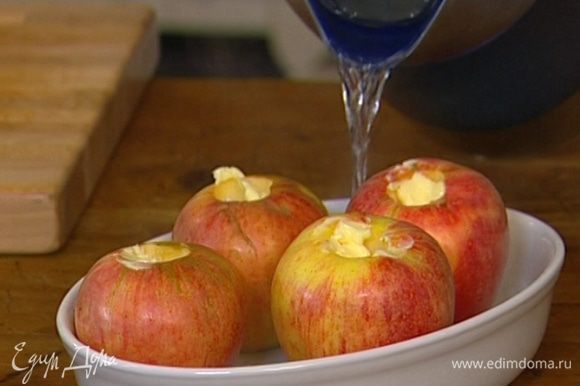 Влить в форму 70-100 мл горячей воды и отправить яблоки в разогретую духовку.