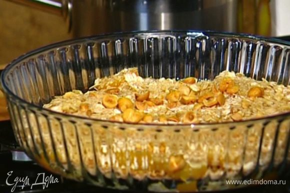 Посыпать фрукты геркулесом, немного полить соком, который остался от персиков, присыпать истолченными орехами. Поставить форму в разогретую духовку.