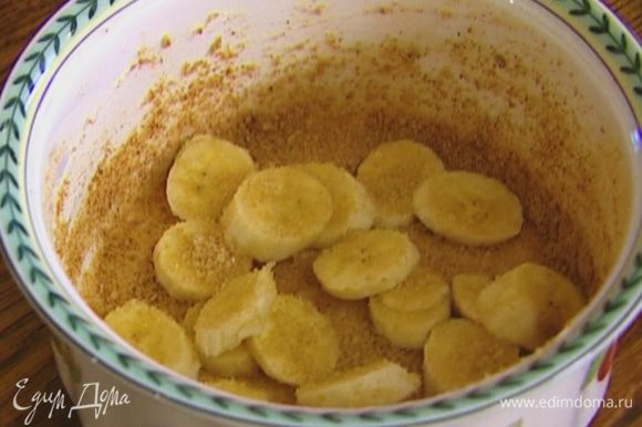 Керамическую форму смазать растительным маслом, присыпать крошкой из печенья (немного оставить), разложить кусочки банана, посыпать 2 ч. ложками сахара.