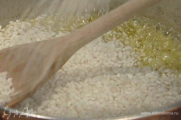 Добавить рис к луку и 2—3 минуты тушить на медленном огне, чтобы рис пропитался ароматом масла и лука.