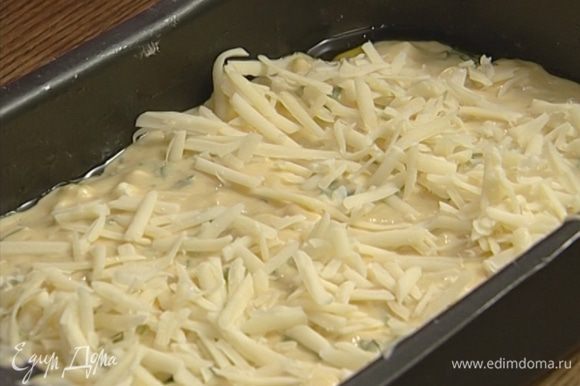 Смазать форму для выпечки оставшимся оливковым маслом, выложить в нее тесто и посыпать швейцарским сыром.