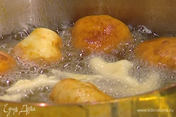 В глубокой сковороде или кастрюле разогреть растительное масло и жарить пончики до золотистого цвета.