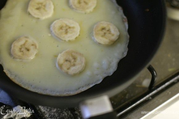 На сковородку наливайте тесто и сразу кладите кусочки бананов, пока блин не схватился. Если сковорода не тефлоновая, в тесто заранее добавьте ложку растительного масла.