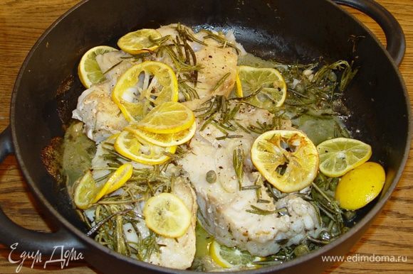Отправить рыбу в разогретую духовку, через 5 минут уложить на нее кружки лимона и запекать еще около 20 минут.