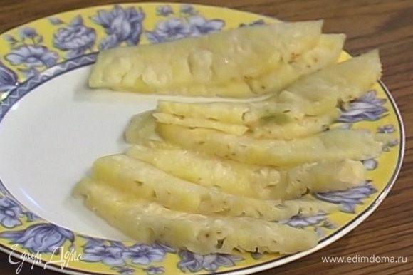 Мякоть ананаса нарезать тонкими ломтиками и выложить в креманку.