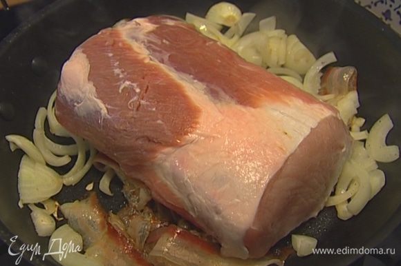Уложить в сковороду кусок свинины и, помешивая лук, обжарить мясо со всех сторон до золотистого цвета.