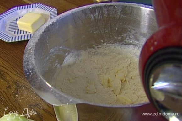 Приготовит тесто: нарезать кубиками 80 г предварительно охлажденного сливочного масла и выложить в чашу комбайна, всыпать оставшуюся муку, сахар, 1 ч. ложку соли и вымешать насадкой-венчиком.