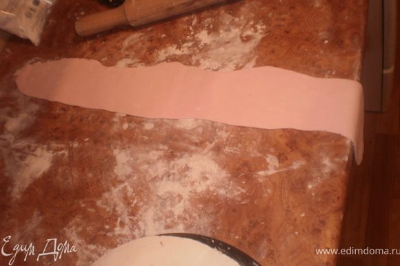Раскатываем розовую мастику по длине окружности торта и шириной чуть больше высоты торта.