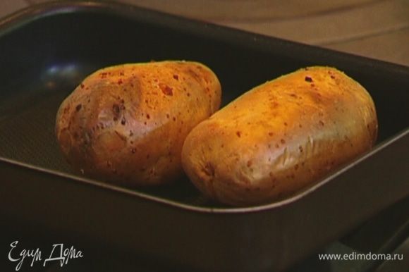 Картофель наколоть вилкой со всех сторон, выложить на противень и отправить в разогретую духовку на 45−60 минут.