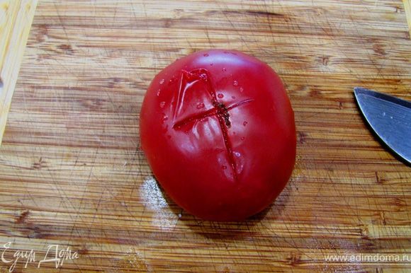 Достаньте помидоры из кипятка и обдайте их холодной водой. Разрежьте кожицу крест на крест.