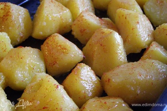 На горячий противень выложим отварной картофель, встряхнем противень, чтобы смешать картофель с маслом. С помощью кисти смажем картофелины шафранным маслом.