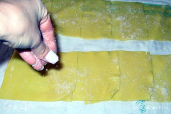 Присыпать тёртым пармезанским сыром. Кроме того, что сыр придаст дополнительный вкус пасте, он ещё и подсушит её, начинка пристанет лучше и будет легче закрутить каннелони.