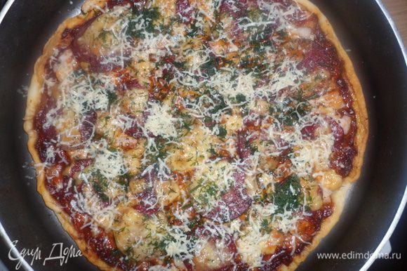 Готовую пиццу посыпаем зеленью и тертым сыром.