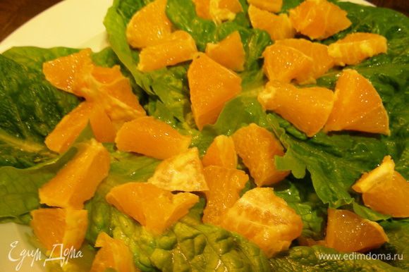 На тарелку выкладываем салатные листья. На них апельсин.
