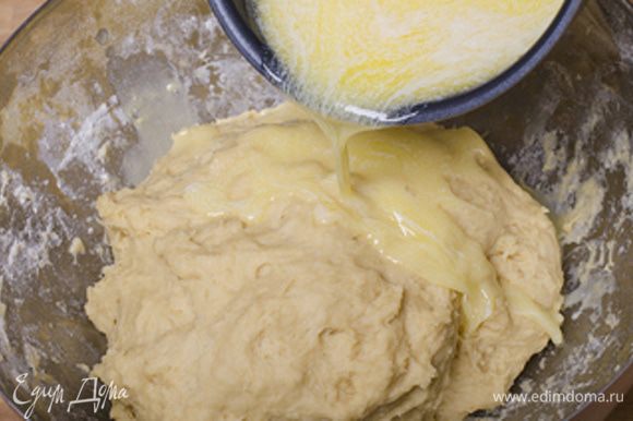 В готовое тесто вливаем постепенно небольшими порциями теплое жидкое сливочное масло, вымешиваем.