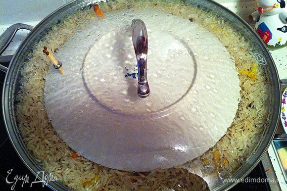 Когда жидкость полностью впитается в рис, делаем лунки в рисе для чеснока и пристраиваем его там. Последний раз разравниваем рис, немного убирая рис с краев в сторону центра и собирая в пологую горку. Делаем 3-5 отверстий до дна казана. Накрываем, заранее приготовленной, тарелкой рис и закрываем Вок крышкой (без отверстий). Делаем температуру на 1 (минимум) и ждем примерно 25 минут. (Для того что бы понять примерно какое время держать плов закрытым, попробуйте рис с шумовки (он наверняка там остался), если рис почти готов лучше уменьшить время ожидания до 18-15 минут, если еще сыроват, то лучше подождать 25 минут)