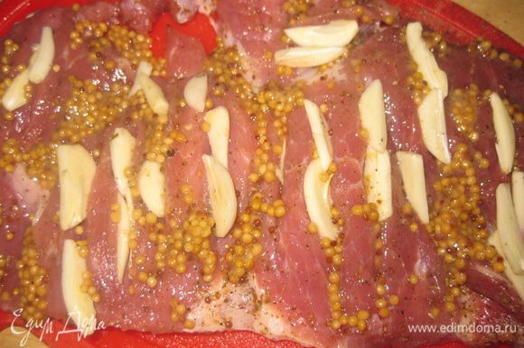 На мясном пласте делаем продольные разрезы, солим, перчим, посыпаем смесью специй для мяса с обеих сторон, и обмазываем зернами горчицы. В продольные разрезы вставляем пластины чеснока.Оставляем мариноваться на 1 час.