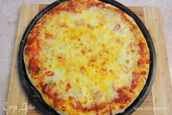 Разогрейте духовку до максимальной температуры. Поставьте в самый низ решетку. Когда печь прогреется - поставьте на решетку пиццу. Выпекайте 7-10 минут (у меня - около 12 минут). За 3 минуты до конца запекания, посыпьте пиццу Пармезаном. Когда сыр подрумянится и снизу пиццы появится аппетитная корочка - снимайте пиццу с огня. Выложите пиццу на блюдо и полейте слегка оливковым маслом. Поперчите пиццу и положите свежие листья базилика.