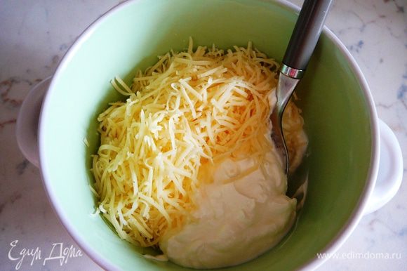 Сыр натереть на мелкой терке. Часть сыра соединить со сметаной и перемешать.
