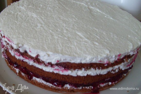 Накрыть третьим слоем, также пропитать его сиропом. Оставшиеся сливки распределить на верх и бока торта.