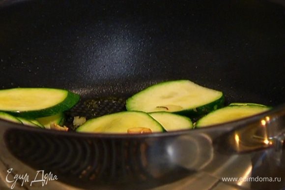 Разогреть в глубокой сковороде оливковое масло, выложить чеснок и цукини и обжарить до легкого золотистого цвета.