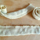 Каждую полоску сложить пополам и защипнуть концы, затем полоски свернуть в клубочек, придавая форму розочки. Уложить все розочки в пароварку и готовить 30-35 минут.