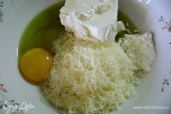 В глубокую чашку натереть сыр на мелкой терке, добавить творог, желток, соль, сахар и оливковое масло, перемешать.