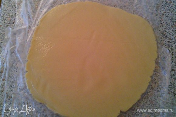 Выкладываем тесто на пищевую плёнку, прикрываем сверху ещё одним слоем плёнки и раскатываем пласт толщиной 0,7см. (без плёнки, тесто пристанет к скалке).