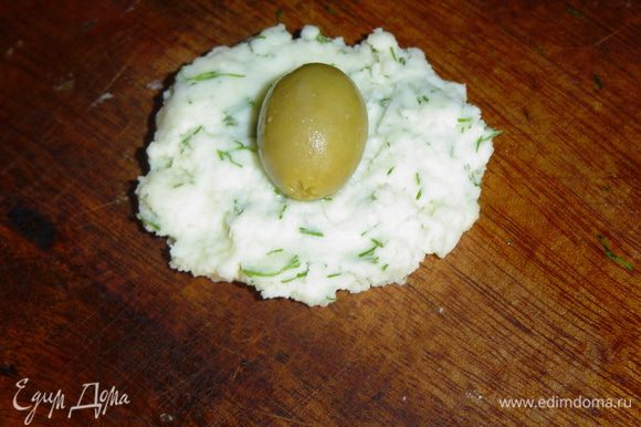 Из сырной массы делаем лепешки, в центр кладем оливки и формируем шарики.