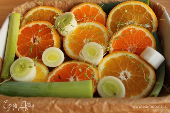 Апельсин, мандарины и порей нарезать толстыми колечками и выложить в форму, застеленную пергаментом.