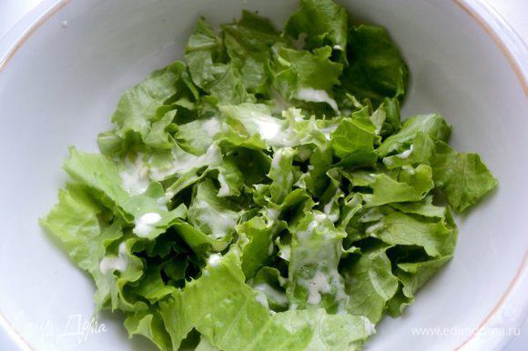 Салат предварительно помыть, обсушить и положить в холодильник. В холодном виде он более хрустящий и дольше сохраняет свежесть. Охлажденный салат порвать руками в салатник, полить немного соусом и перемешать.