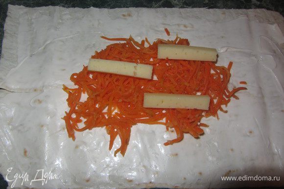 Сыр порезать длинными ломтиками и выкладывать по пару кусочков на морковку.