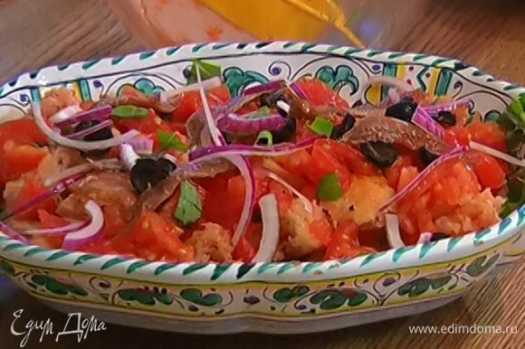 Сверху на салат выложить оставшиеся помидоры и базилик, оливки, анчоусы, красный лук. Все перемешать и сразу подавать.