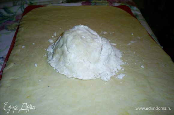 Когда тесто подойдет, раскатываем его в прямоугольный пласт толщиной около сантиметра, на его средину выкладываем комок из масляной крошки.