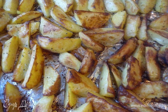 Лист застелить фольгой, смазать ее маслом. Выложить картофель в один слой. Запечь в духовке при 220 С почти до готовности.