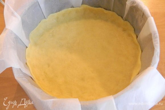 В форму, застеленную пекарской бумагой, выкладываем тесто и пальцами равномерно распределяем по всему дну, делая небольшие бортики.