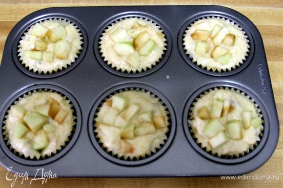 Раскладываем приготовленное тесто в формы для маффинов и сверху кладем оставшиеся яблоки.