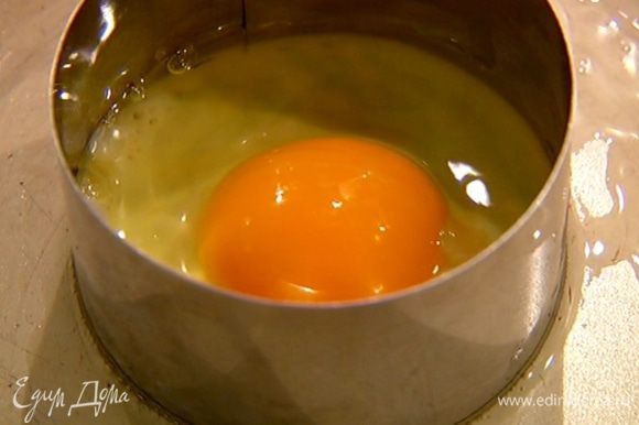Разогреть в сковороде оставшееся оливковое масло, поместить в нее 4 кондитерских кольца, разбить в них по яйцу и пожарить.
