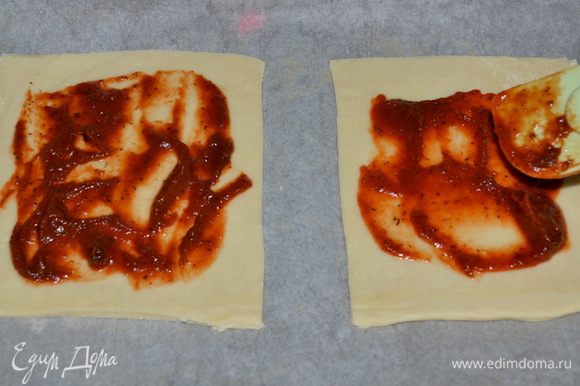Раскатываем тесто, затем разрезаем на квадраты, должно выйти 6 квадратов. Каждый квадрат смазываем кетчупом или томатным соусом по центру,не задевая кончики краев.