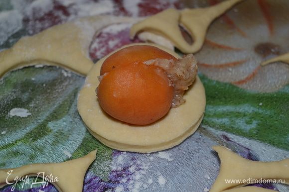 Тесто раскатывем толщиной примерно 0,7-0,8 см. С помощью стакана вырезаем круги. В каждый круг кладем абрикос с начинкой.