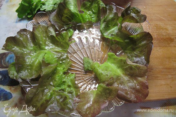 На тарелку выкладываем листья салата. Вынимаем из бульона курицу, даем ей остыть и нарезаем тонкими ломтиками.