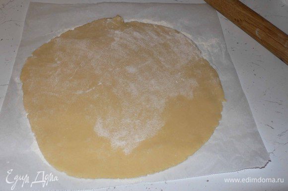 Раскатываем на пекарской бумаге два диска диаметром около 22 и 24 см. Обмазываем маслом и обсыпаем мукой невысокую форму.