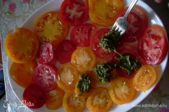 Нарезать помидоры кружочками и разложить на плоском блюде. На каждый кусочек сверху добавить немного песто.