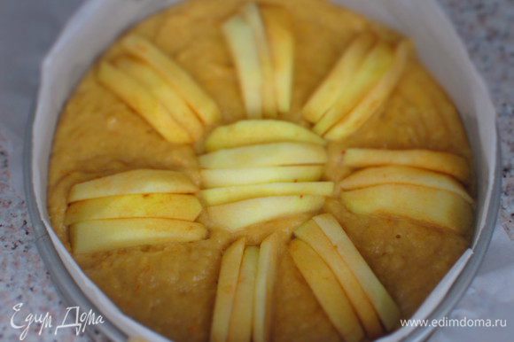 Вылить тесто в форму с пергаментом и сверху выложить оставшуюся часть яблок. Выпекать в разогретой до 180°С духовке 50 минут.
